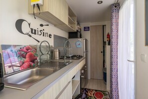 A compact kitchen with a stainless steel sink, a gas stove, and a small refrigerator.