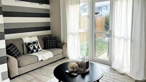 A living room with a sofa, a round coffee table, and a sliding glass door leading to a backyard.