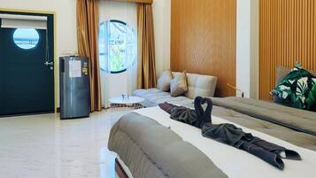 Habitación de hotel con cama, una mesita redonda, refrigerador y ventana con cortinas.
