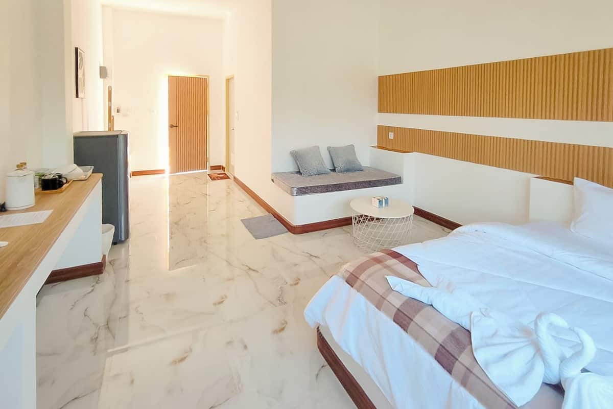 Habitación de hotel con cama, escritorio, un pequeño espacio de descanso y vista al pasillo.