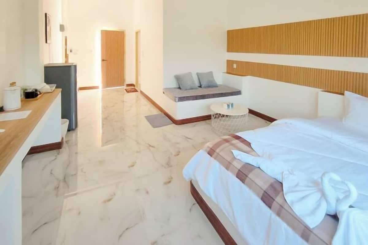 Una habitación de hotel con cama, escritorio, zona de estar y puerta.