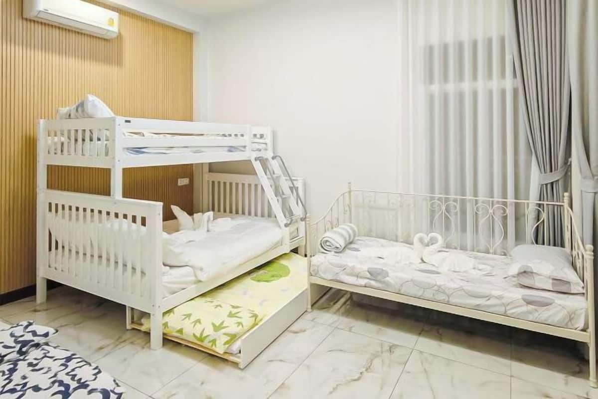 Una habitación con dos literas, un panel de pared de madera, una ventana con cortinas y suelo de baldosas.