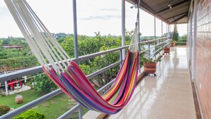 A balcony with a hammock, potted plants, and a view of greenery. - Hotel campestre sueño del abuelo (Pereira)