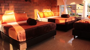 A hotel room with three beds, a brick wall, and a view of the outside. - Hotel campestre sueño del abuelo (Pereira)