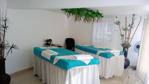A spa room with two massage tables, a potted plant, a fan, and a decorative cushion. - Hotel campestre sueño del abuelo (Pereira)