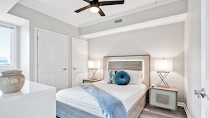 A bedroom with a bed, bedside tables, a ceiling fan, and a window. - Battleship Sunset on Water Street! River View! Free parking!! (Wilmington)