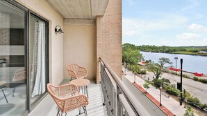 A balcony with wicker chairs and a view of a river. - Battleship Sunset on Water Street! River View! Free parking!! (Wilmington)