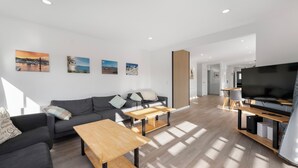 Ein modernes Wohnzimmer mit Sofa, Couchtisch, Fernseher und Kunstwerk an der Wand.
