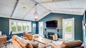 A living room with a fireplace, leather sofas, a coffee table, and a TV mounted on the wall. - Modern Deluxe - Havelock North Holiday Home (Havelock North)