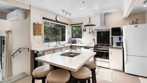 Une cuisine moderne dotée d’un îlot central, de tabourets de bar, d’une cuisinière et d’un réfrigérateur.