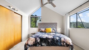 Une chambre dotée d’un grand lit, d’un ventilateur de plafond et offrant une vue sur l’extérieur.