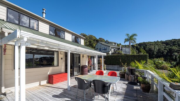 Une terrasse en bois avec un espace patio couvert, des sièges d’extérieur et des plantes en pot.