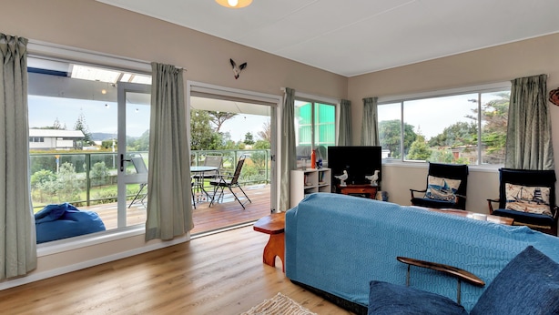 Una habitación amplia con una cama grande, piso de madera y vistas a un balcón con mobiliario exterior.