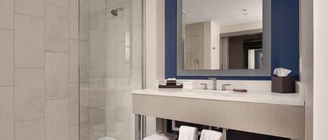 A modern bathroom with a glass shower enclosure, a large mirror, and a vanity with a towel rack.