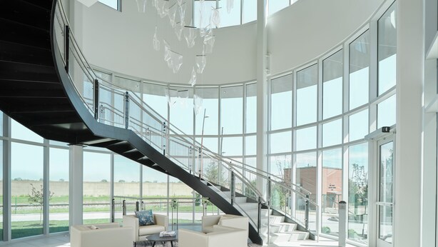 A spacious lobby with a curved staircase, large windows, and a seating area with a rug. - The Riverview (Cape Girardeau)