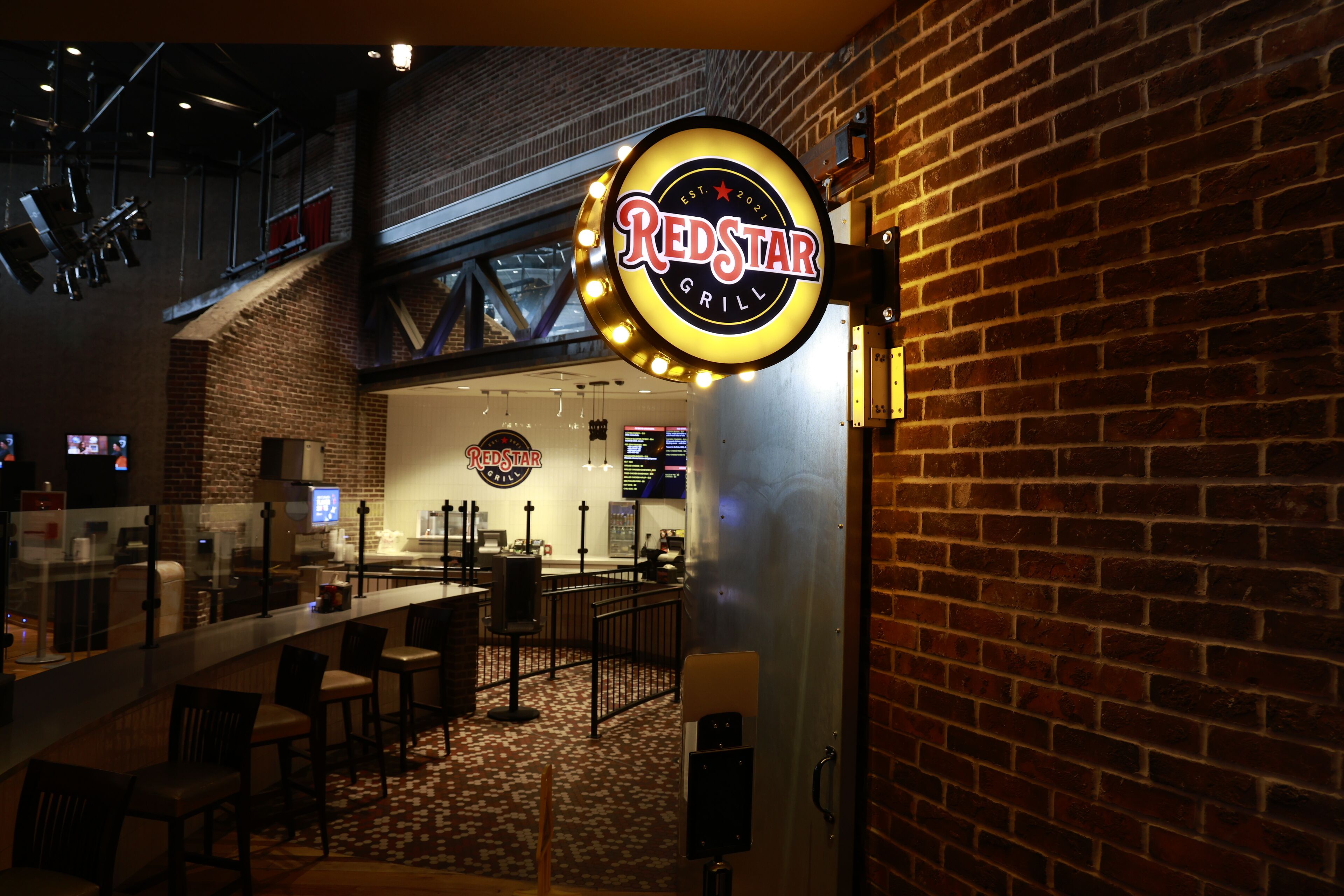 Un RedStar Grill avec un mur en briques et un coin bar doté de tabourets.