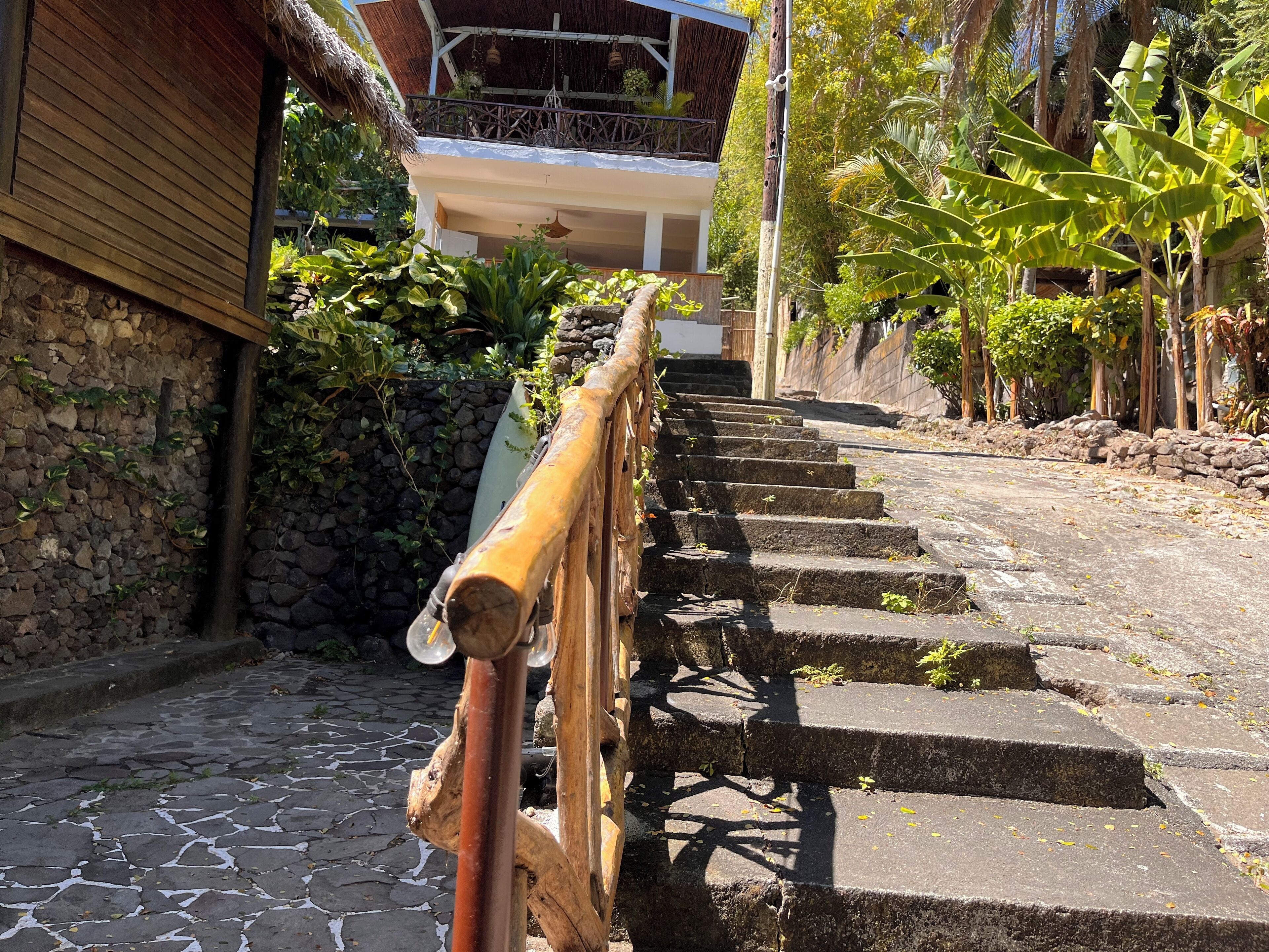 A stone staircase leading up to a building with a wooden handrail.