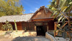 A rustic building with a thatched roof, a stone-paved courtyard, and a wooden fence.