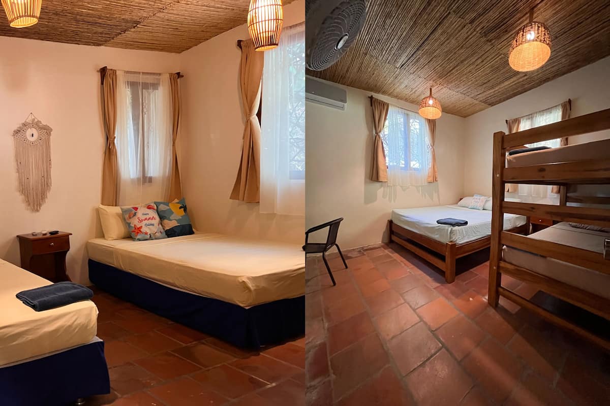Een kamer met twee bedden, een klein tafeltje, een macramé wanddecoratie en een plafondventilator.