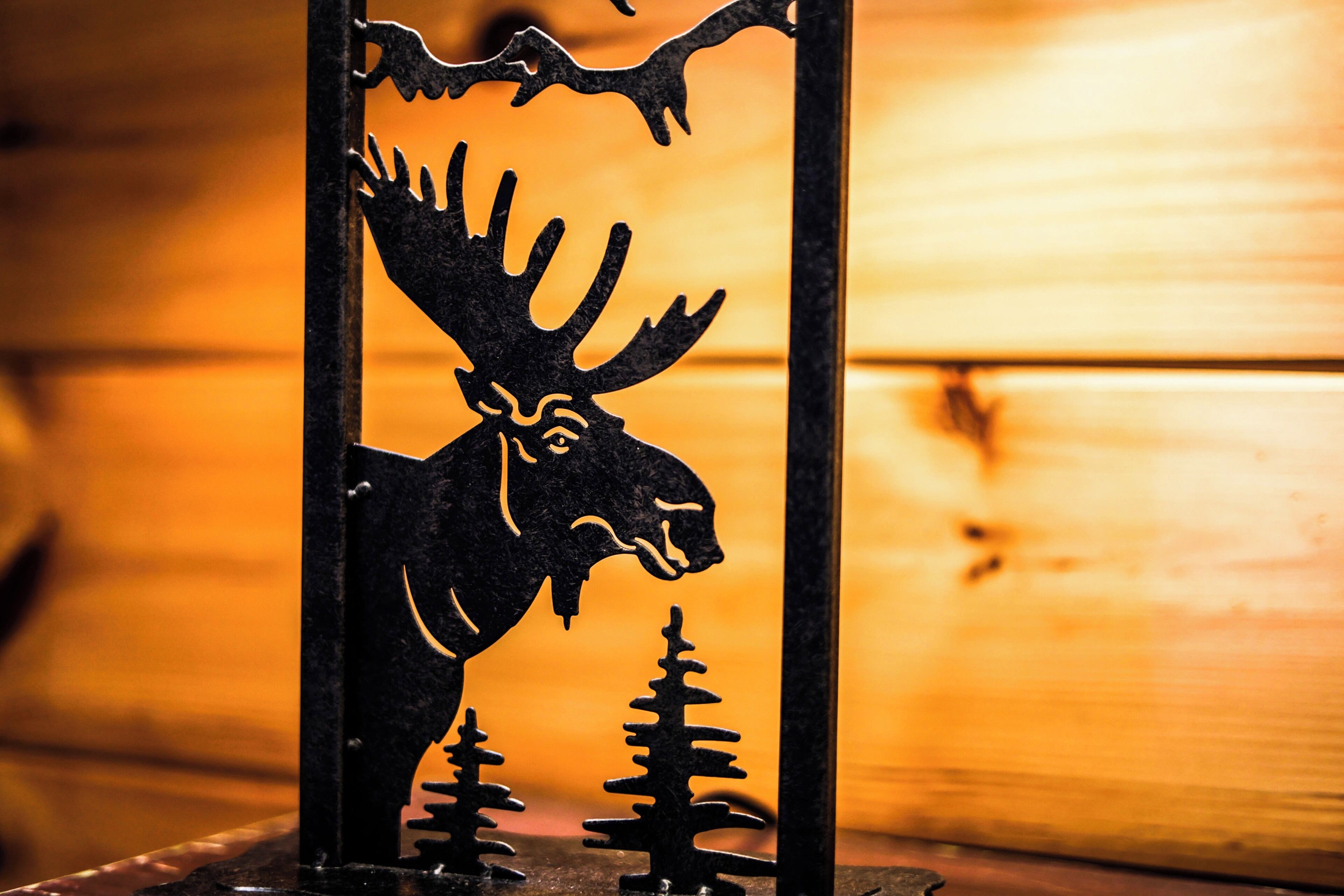 A moose silhouette mounted on a metal frame with trees in the background.
