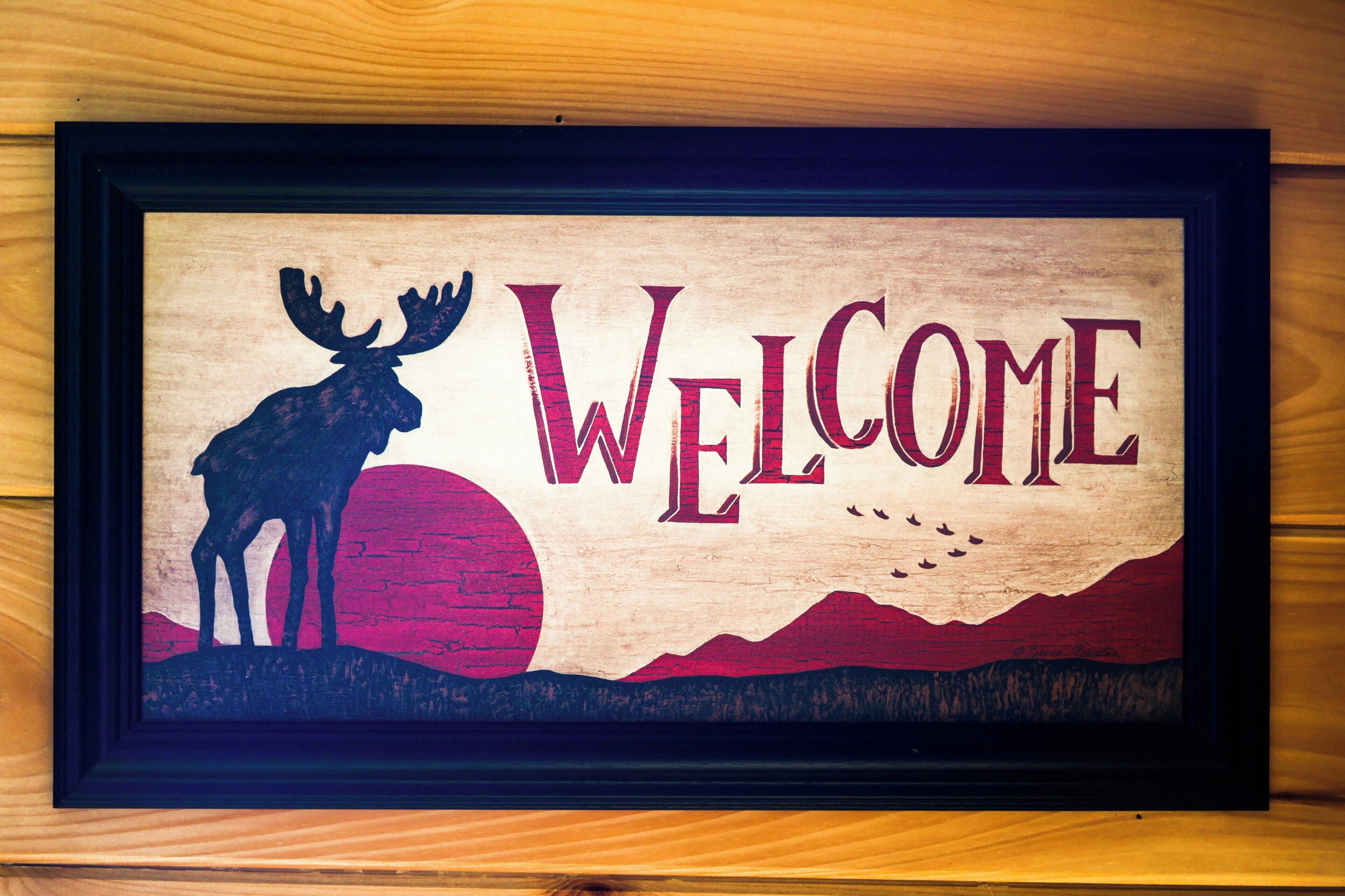 Un letrero de bienvenida enmarcado con la silueta de un alce y la palabra 'WELCOME' en letras grandes.