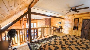 A wooden cabin with a loft bedroom, a balcony, and a fan. - Historic barn at Moosehead Lake (Greenville)