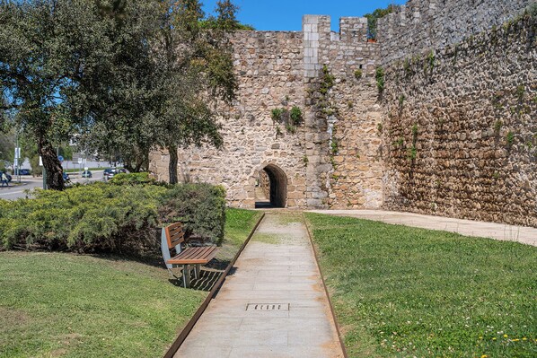 A stone wall with an arched entrance, a pathway, and a bench.