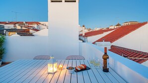 Une terrasse sur le toit, avec une table dressée pour le dîner, une bouteille de vin et une lanterne.