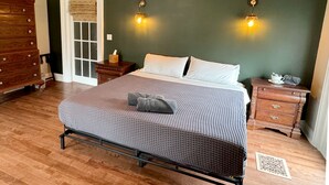 Une chambre à coucher comprenant un lit, une commode en bois, des tables de chevet et deux appliques murales.