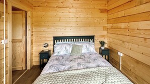 A wooden-paneled room with a bed, a nightstand, a mirror, and a small table with a plant. - 2 bedroom accommodation in Seascale, near Gosforth and Wasdale (Seascale, near Gosforth and Wasdale)