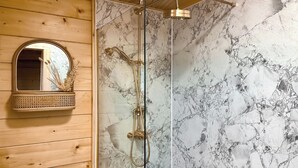 A bathroom with a wooden vanity, a marble shower wall, and a glass-enclosed shower. - 2 bedroom accommodation in Seascale, near Gosforth and Wasdale (Seascale, near Gosforth and Wasdale)
