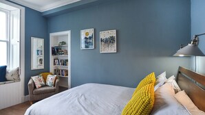 Quarto com uma cama, estante e duas obras de arte penduradas na parede.