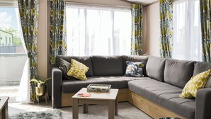 A modern living room with a sectional sofa, a coffee table, and a potted plant. - 2 bedroom accommodation in East Heslerton (East Heslerton)