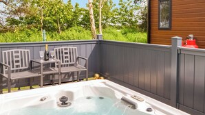 A hot tub with a control panel, two chairs, and a table with a bottle and glass. - 2 bedroom accommodation in East Heslerton (East Heslerton)