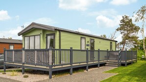 A single-story mobile home with a fenced deck, a small porch, and a gravel driveway. - 2 bedroom accommodation in East Heslerton (East Heslerton)