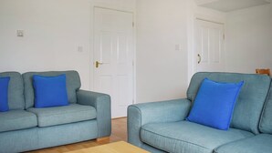 Une pièce avec deux canapés bleu clair, chacun agrémenté d’un coussin bleu, et une table basse en bois.