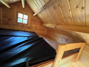 Et træhus indeni med en seng, et lille bord og et vindue.