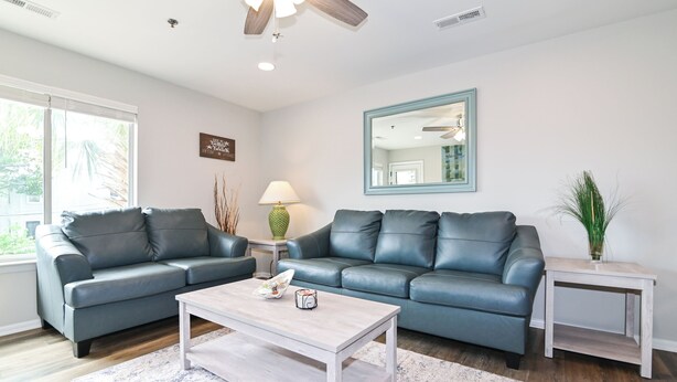 A living room with two dark grey leather sofas, a light wooden coffee table, and a small white side table. - Bright 2BR Retreat w/ Pool – 1.5 Blocks to Oceanfront & Boardwalk (Virginia Beach)