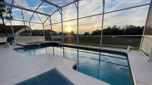 A swimming pool with a view of the sunset, surrounded by a covered area with lounge chairs. - 4BR Villa Bright and Spacious w/ Pool (Davenport)