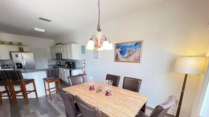 A dining area with a wooden table and chairs, a chandelier, and a painting on the wall. - 4BR Villa Bright and Spacious w/ Pool (Davenport)
