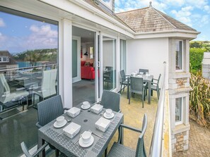A balcony with a dining table set for four, surrounded by wicker chairs.