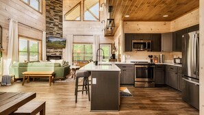 A spacious kitchen with a central island, modern appliances, and a cozy living area with a sofa and a fireplace. - WizardsWelcome~FallSale~HarryPotter~Heated Indoor Pool~HotTub~5minstoPkwy (Pigeon Forge)