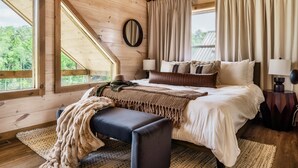 A bedroom with a large bed, a bench, a mirror, and curtains. - WizardsWelcome~FallSale~HarryPotter~Heated Indoor Pool~HotTub~5minstoPkwy (Pigeon Forge)