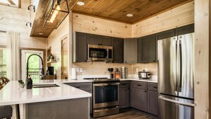 A modern kitchen with stainless steel appliances, wooden cabinetry, and a large island. - WizardsWelcome~FallSale~HarryPotter~Heated Indoor Pool~HotTub~5minstoPkwy (Pigeon Forge)