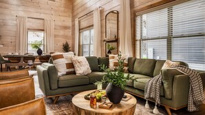A cozy living room with a green sofa, wooden coffee table, and a dining area with a table and chairs. - WizardsWelcome~FallSale~HarryPotter~Heated Indoor Pool~HotTub~5minstoPkwy (Pigeon Forge)