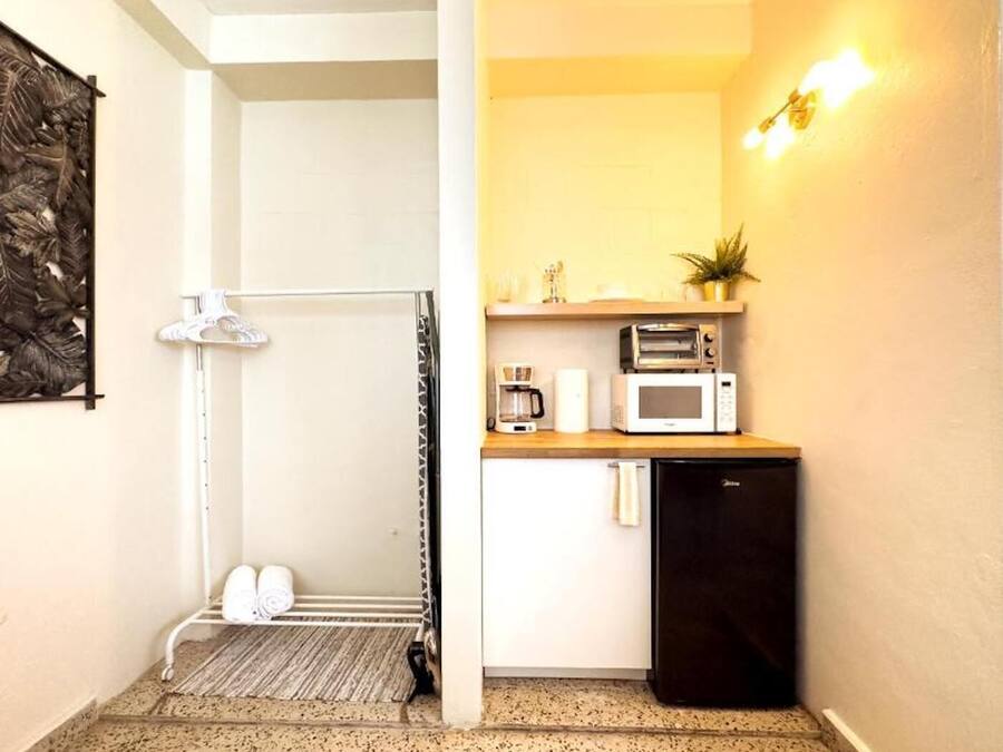 A compact kitchen with a microwave, toaster, and coffee maker on a wooden countertop.