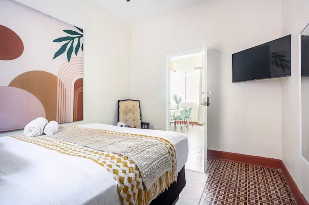 Une chambre d’hôtel avec un lit, un téléviseur fixé au mur et une vue sur l’extérieur.