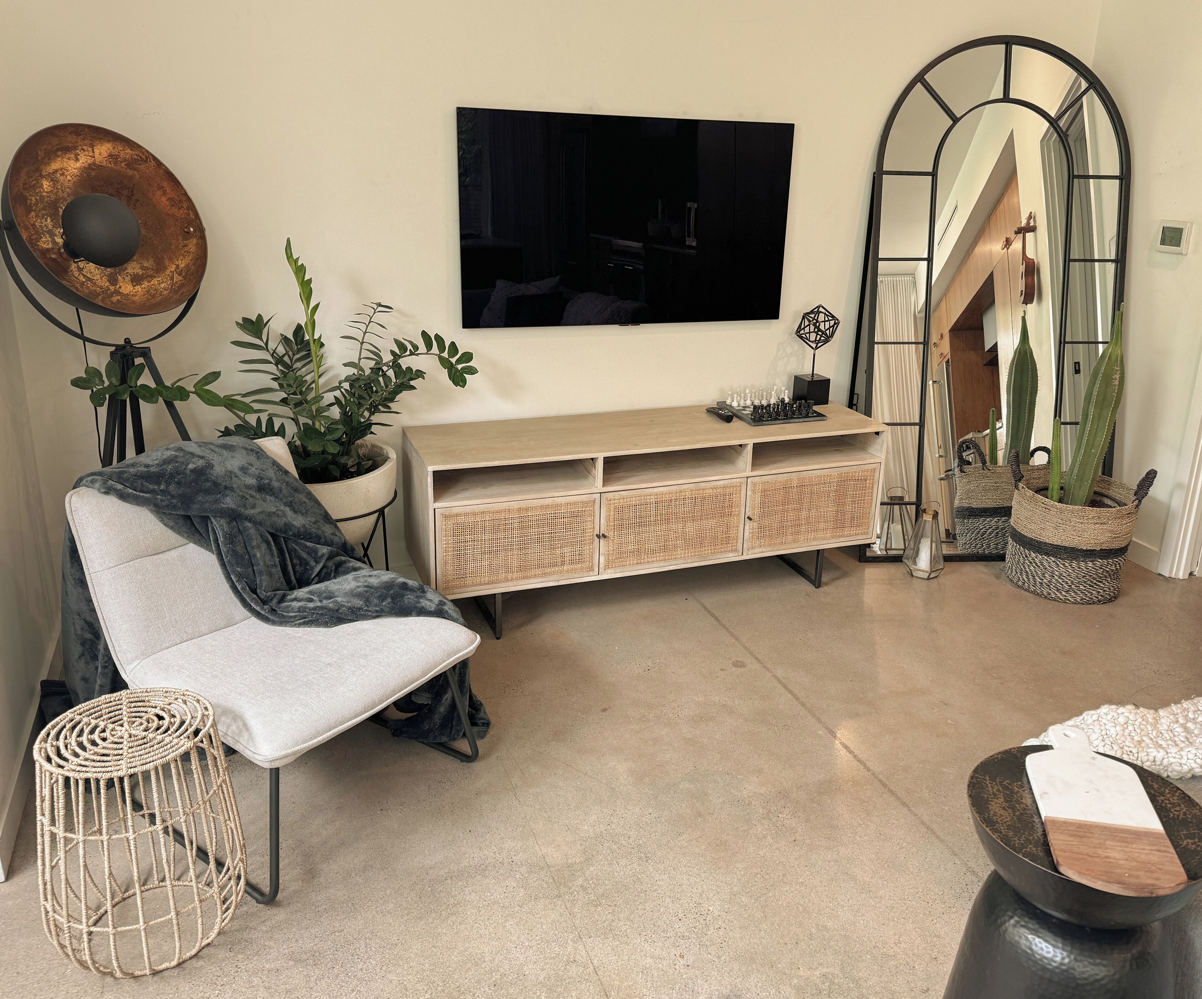 Un salon moderne comprenant un canapé, une table basse, un téléviseur, une console et un grand miroir.