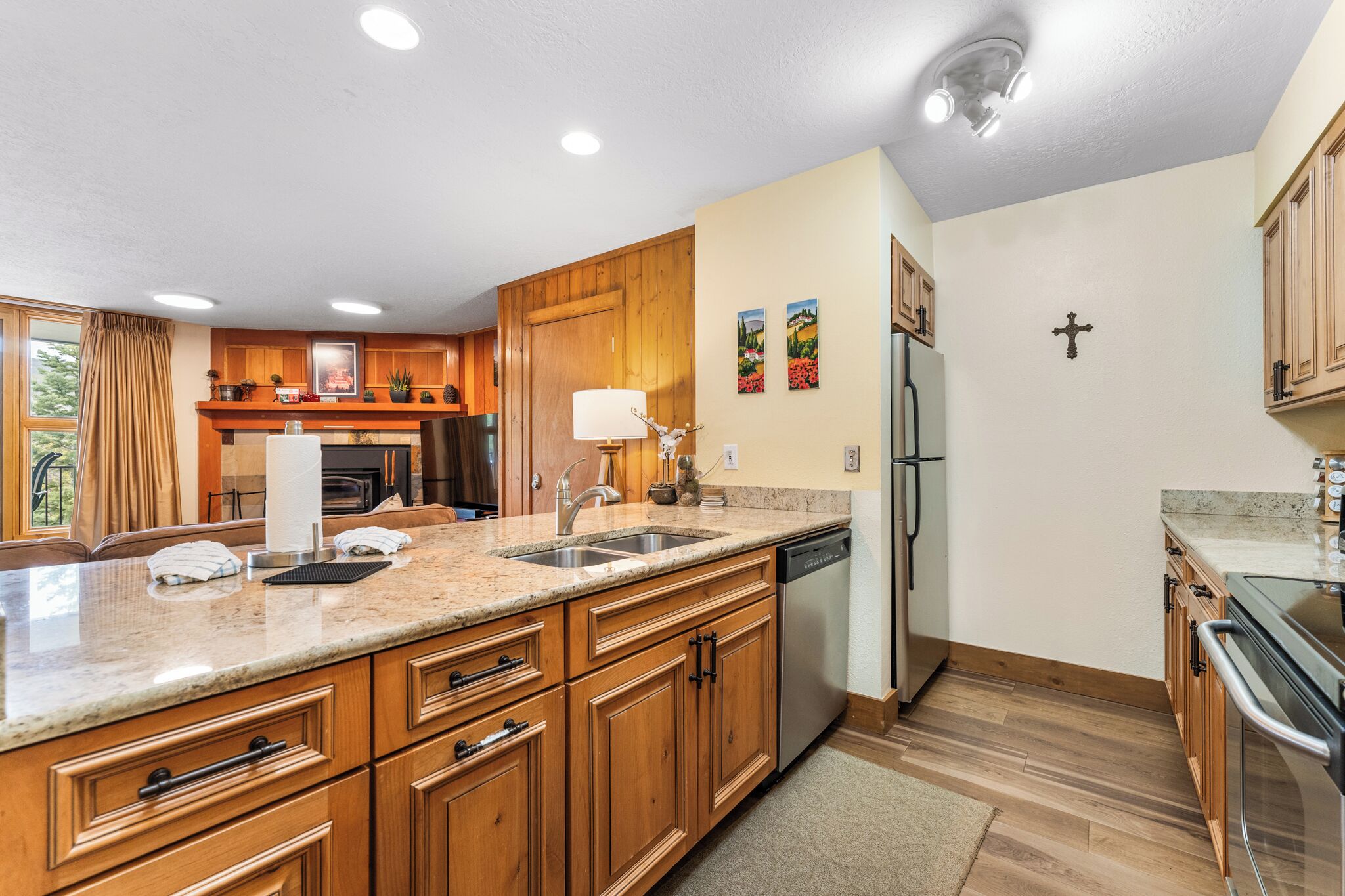 A modern kitchen with wooden cabinets, granite countertops, stainless steel appliances, and a large island with a sink.