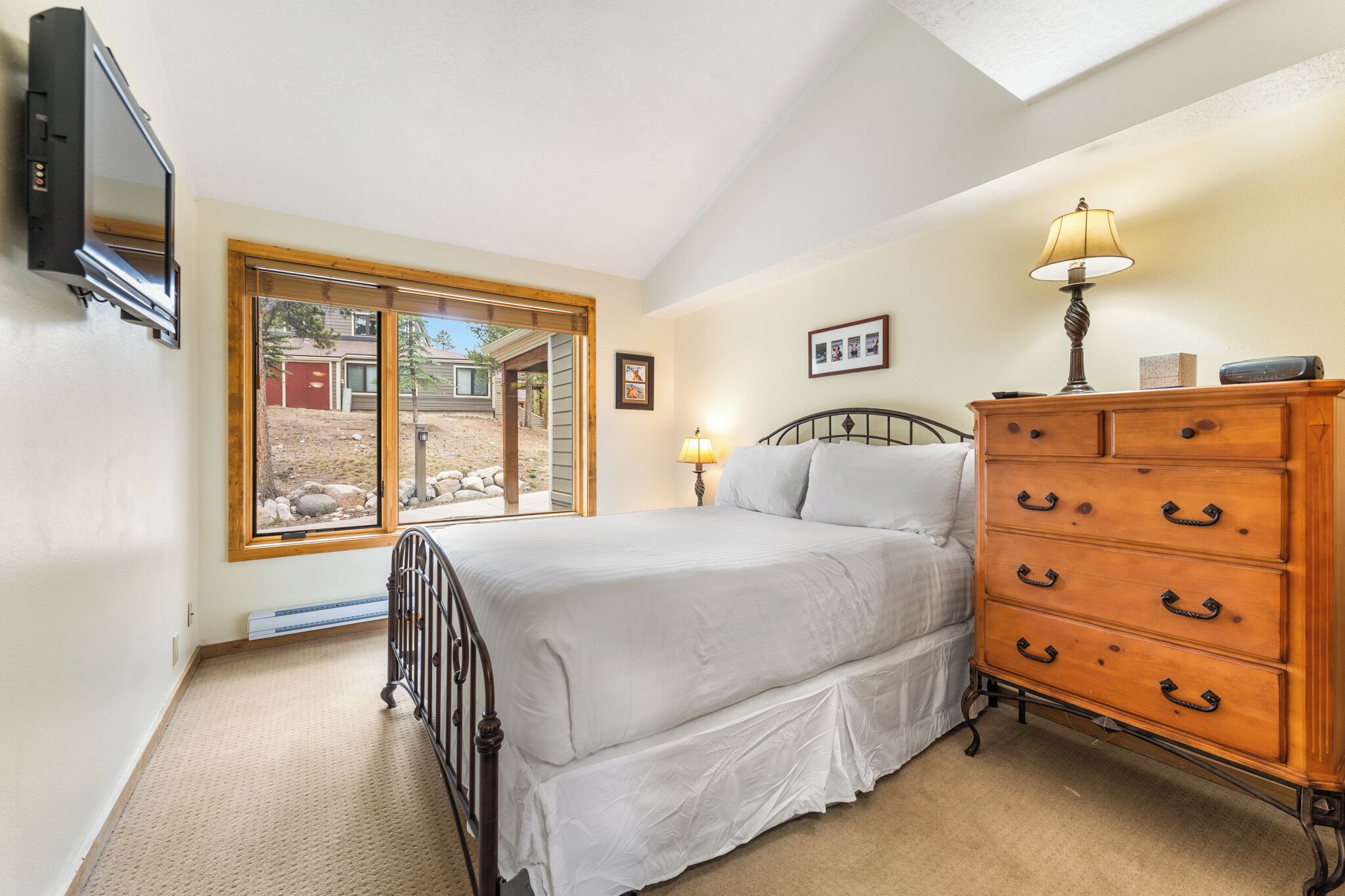 Une chambre à coucher avec un lit, une commode, une lampe et un téléviseur.